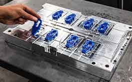 blue injection molding parts being removed from mold block.