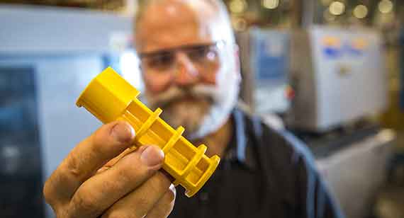 technician holding yellow injection molded part from China Metal Parts